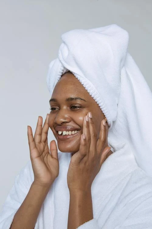 black woman in a robe touching her face that's glowing from acne skincare products
WHat is hyaluronic acid