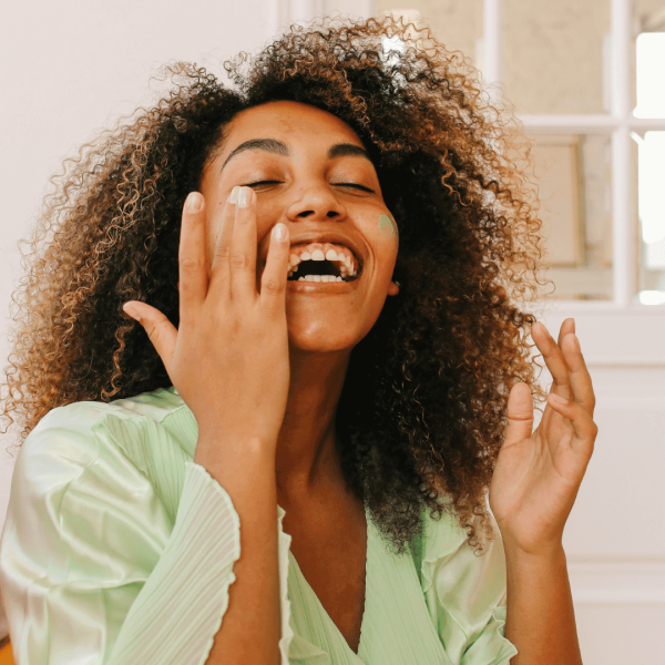 black woman touching her face and smiling